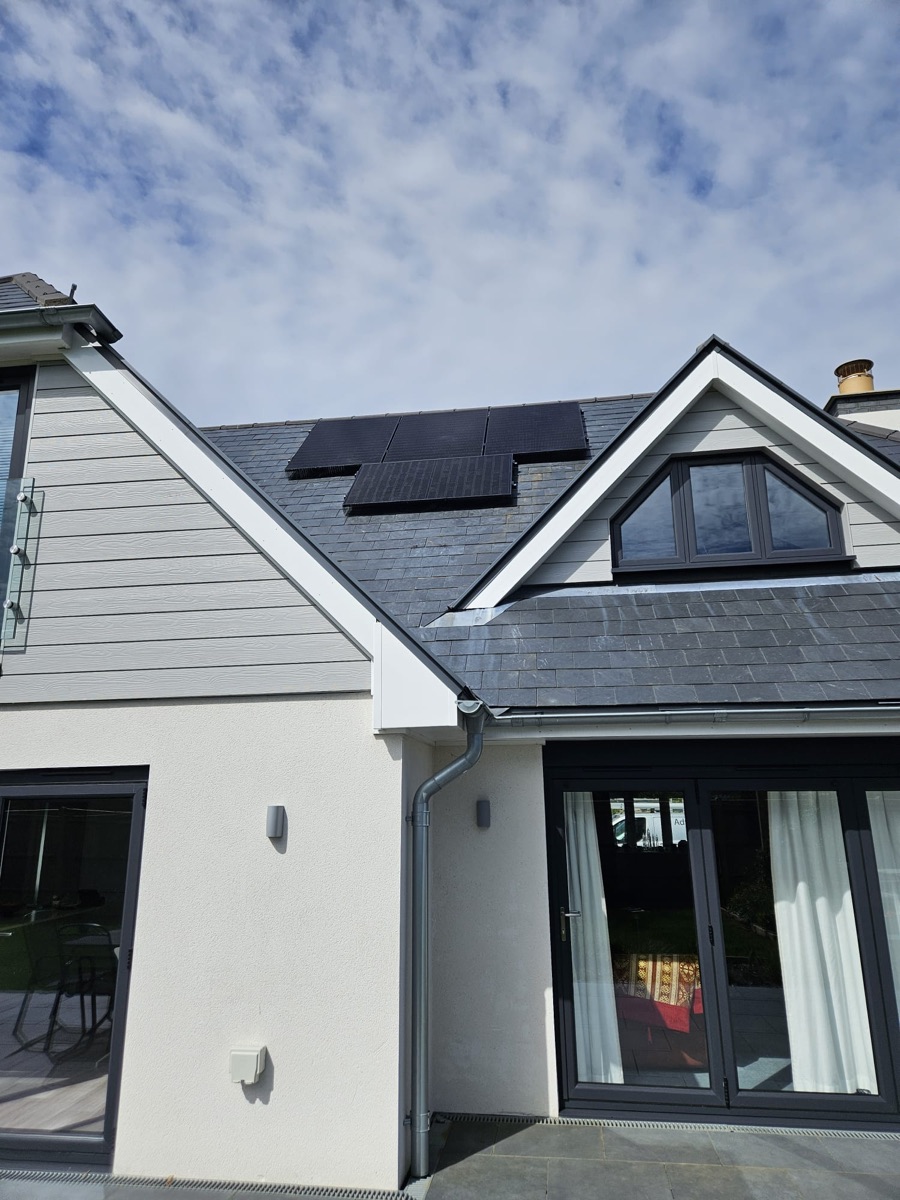 Solar panels on a slate roof above a white rendered house