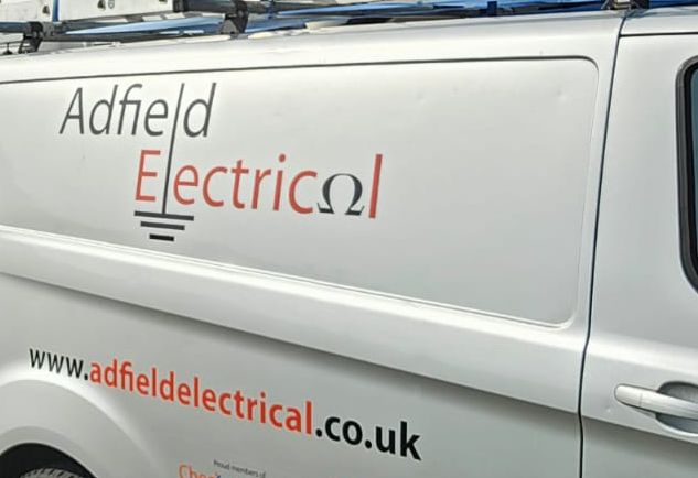 The side of the white Adfield Electrical van, lettered with the logo and its earth symbol